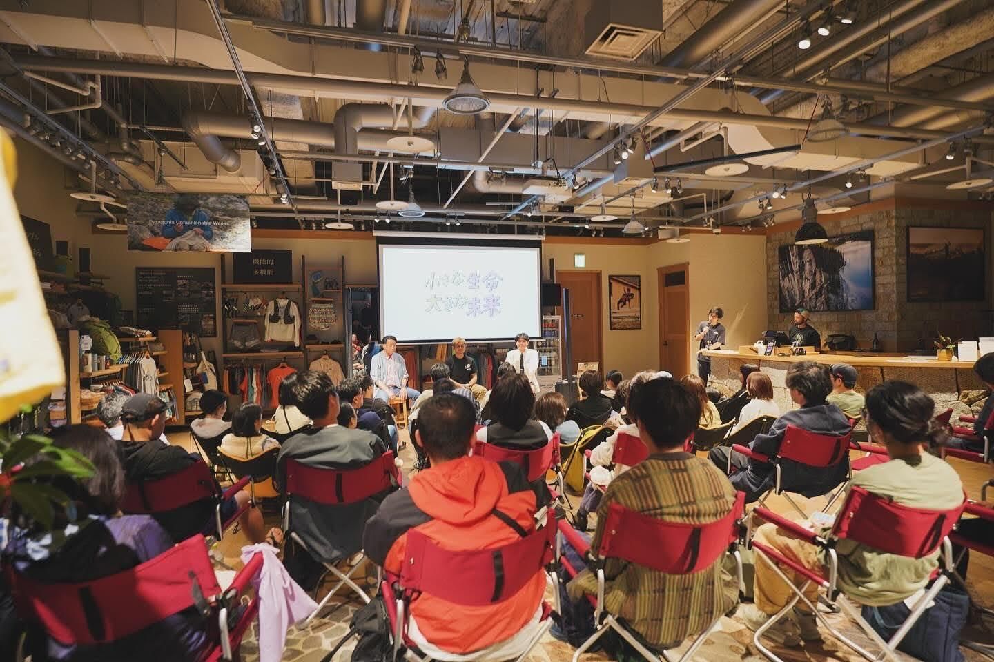 大勢の人が集まり、スクリーンに映像が映し出された会場の様子